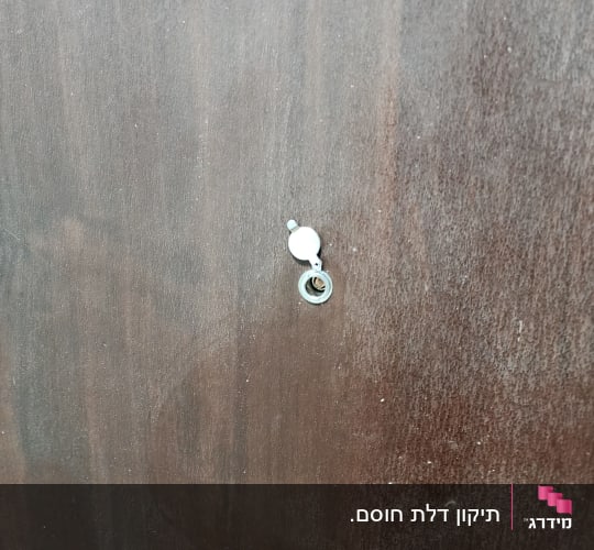 עינית הצצה סטנדרטית מותקנת בדלת עץ חומה